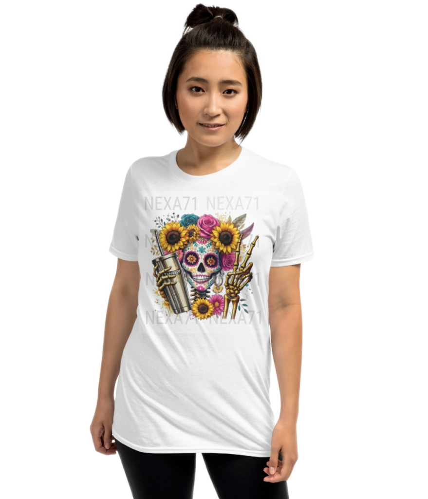 A white tshirt featuring a vibrant floral sugar skull design adorned with sunflowers and roses. The skeleton holds a gold Stanley cup with a straw in one hand and flashes a peace sign in the other. The design blends boho, spooky, and trendy aesthetics, making it a unique statement piece.