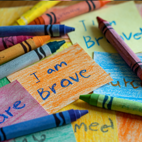 Affirmation words written beside crayons in various tones.
