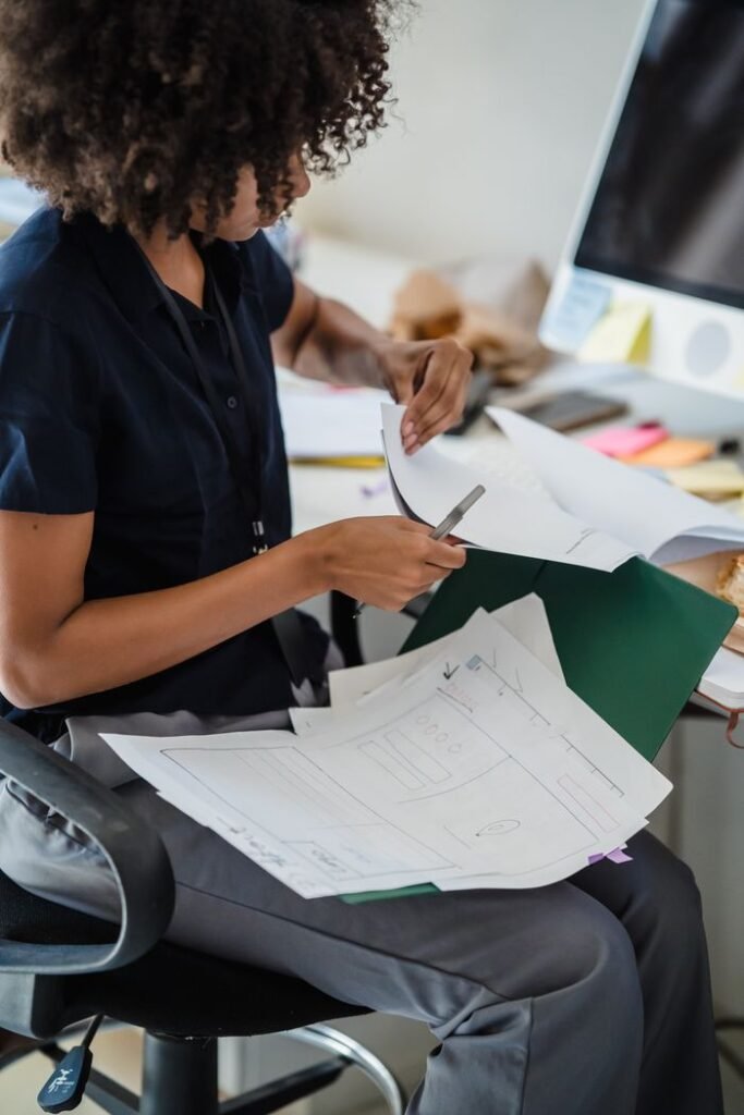 Businesswoman organizing documents at her office desk for efficient workflow.