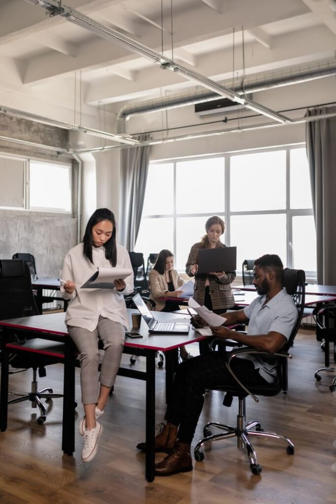 Diverse professionals collaborating in a bright, modern office space, using digital devices and documents.
